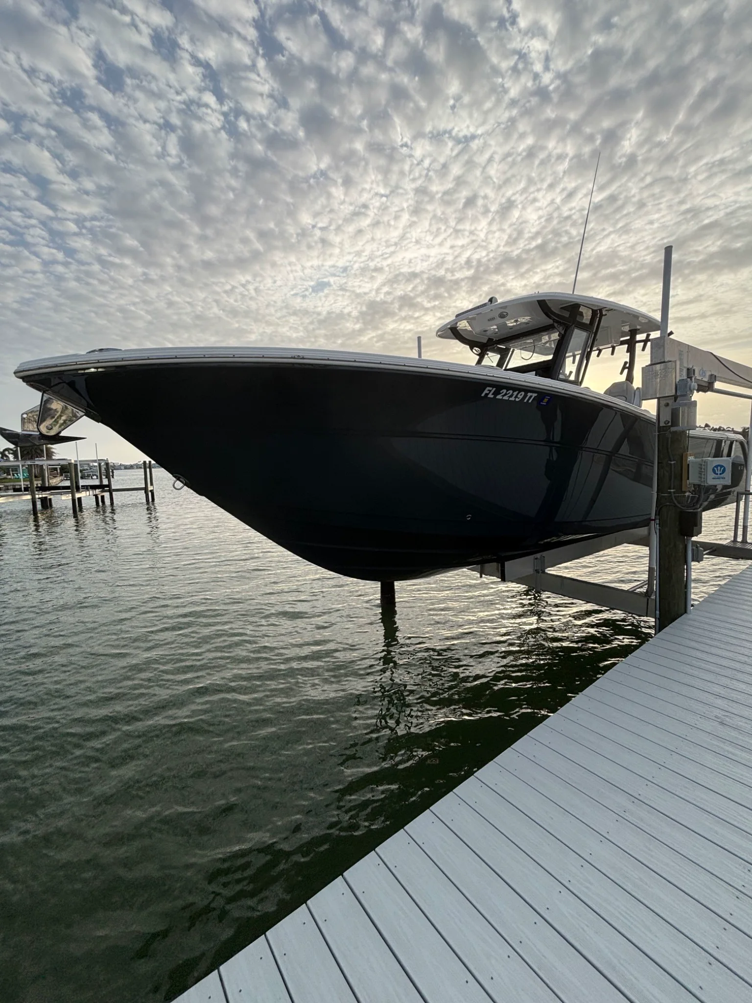 Dark-hull center-console boat on a waterfront lift at sunset