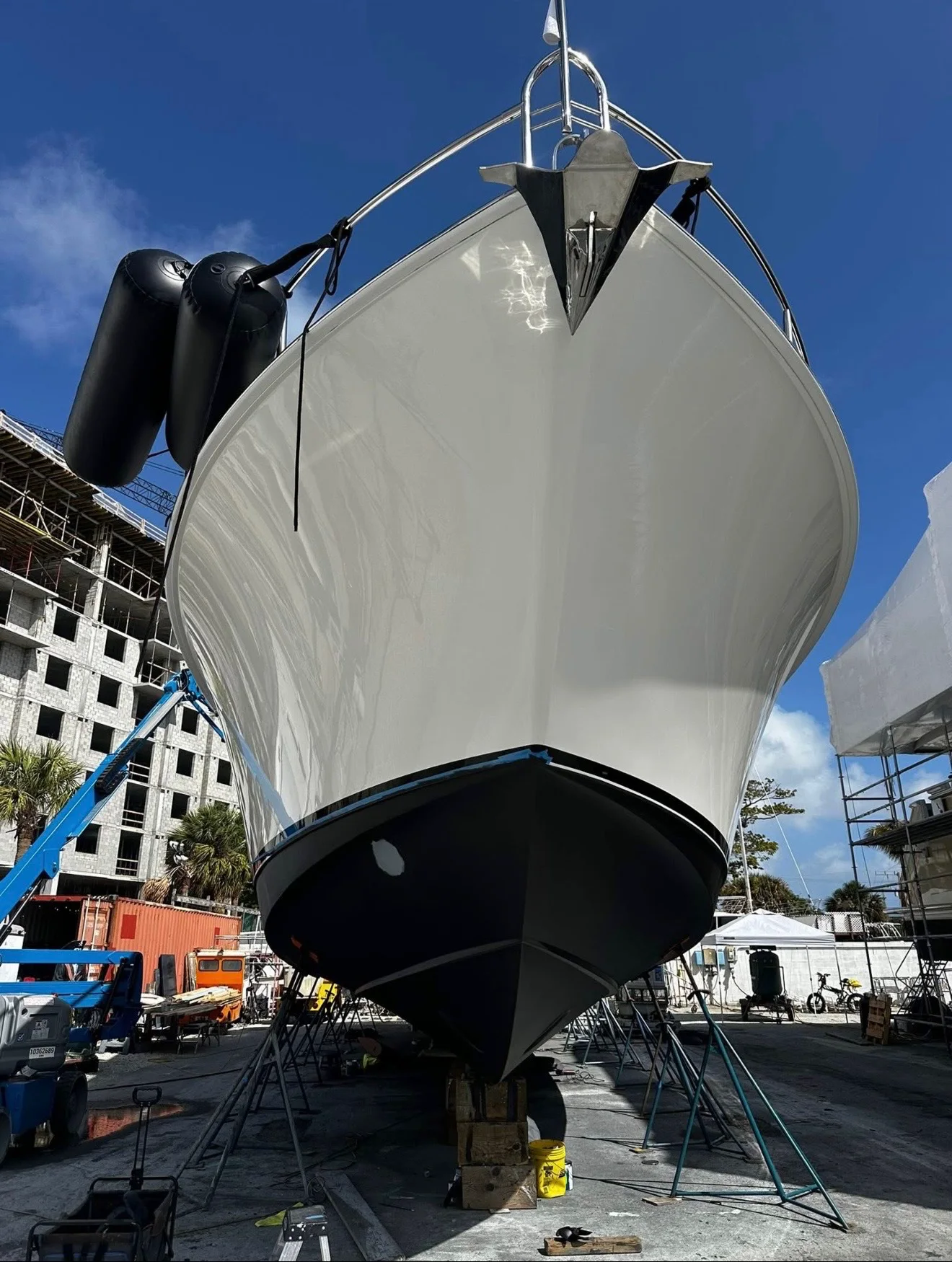 Large white yacht bow with a refined finish while supported in a boatyard
