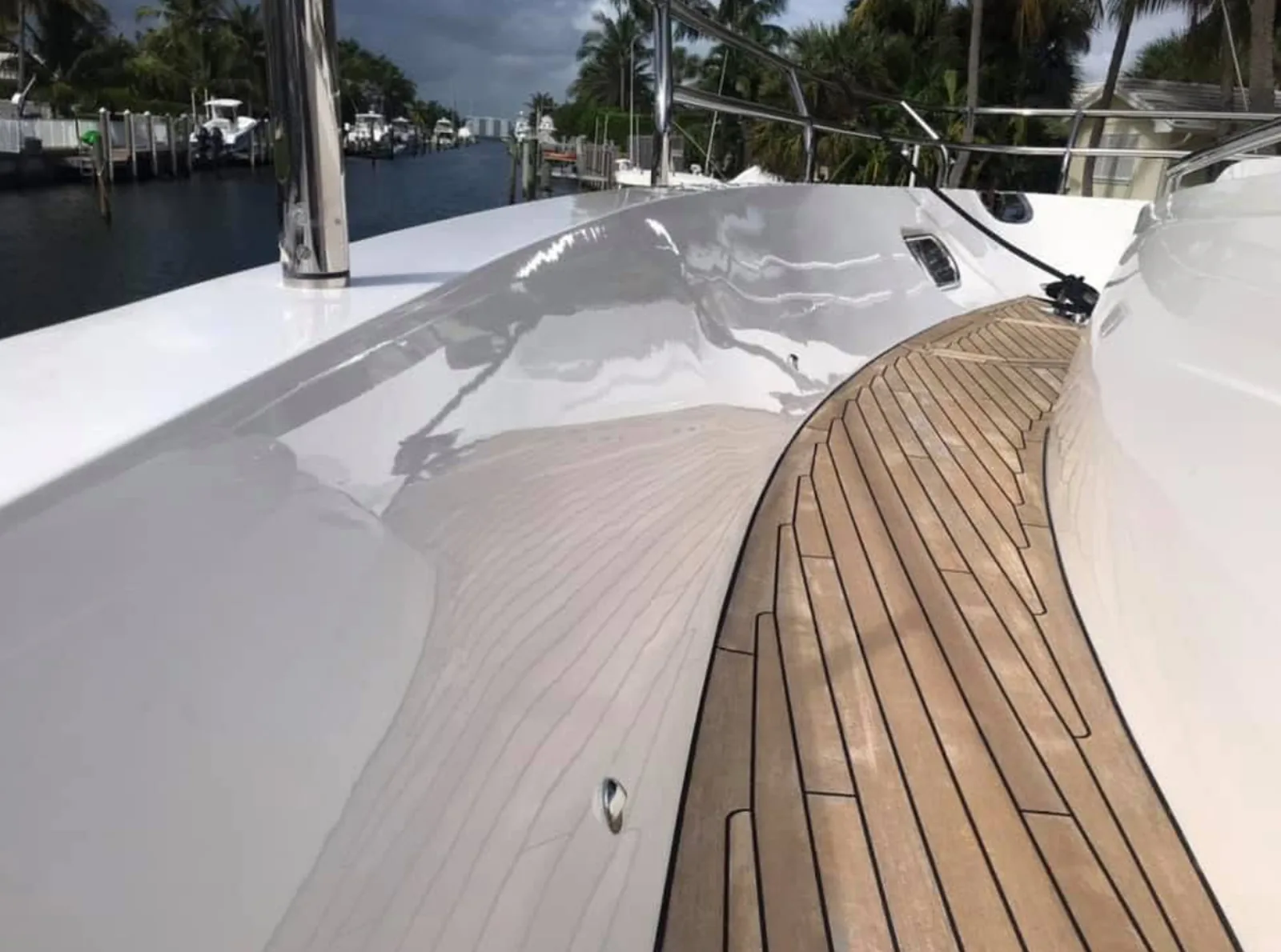 View along a white boat side deck with wood-toned decking beside the water