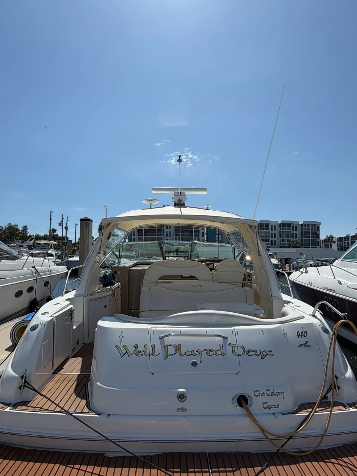 White motor yacht docked at a marina beneath a clear blue sky