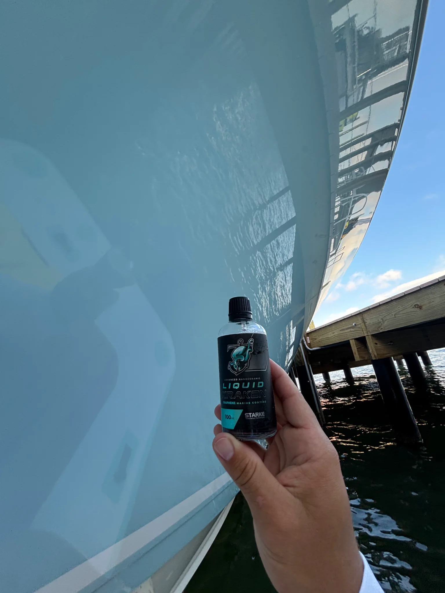 Marine coating product held beside a glossy light-blue hull