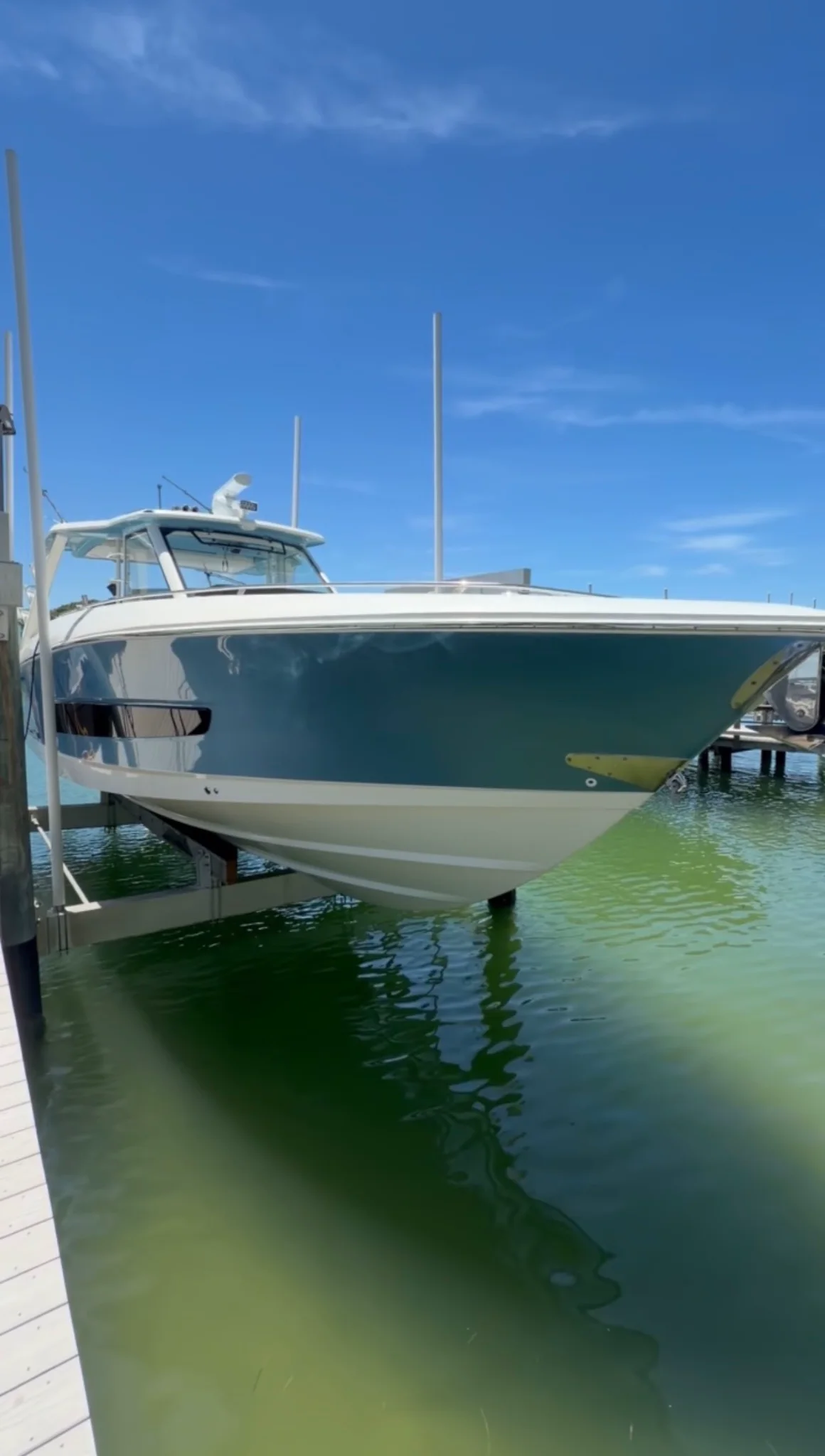 Glossy blue-and-white center-console boat presented on a waterfront lift