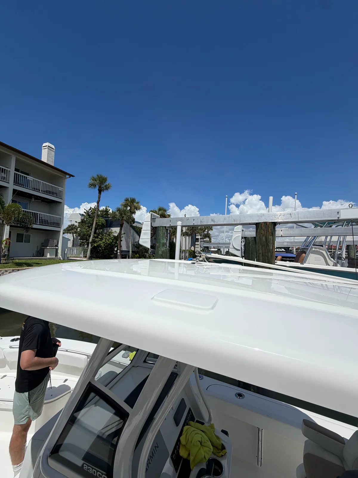White boat docked near a waterfront building with a person standing on deck