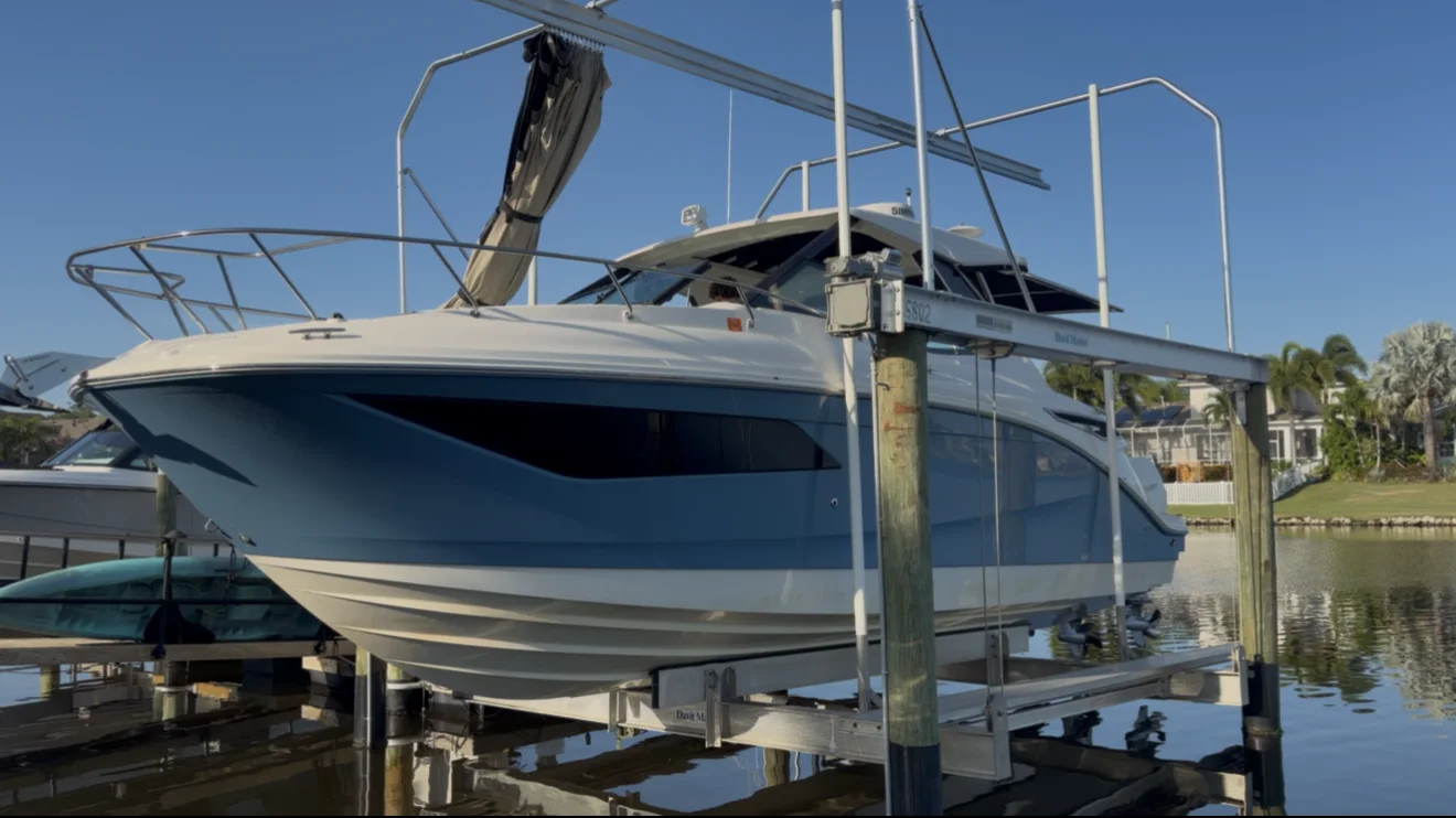 Blue-and-white express cruiser presented on a residential boat lift