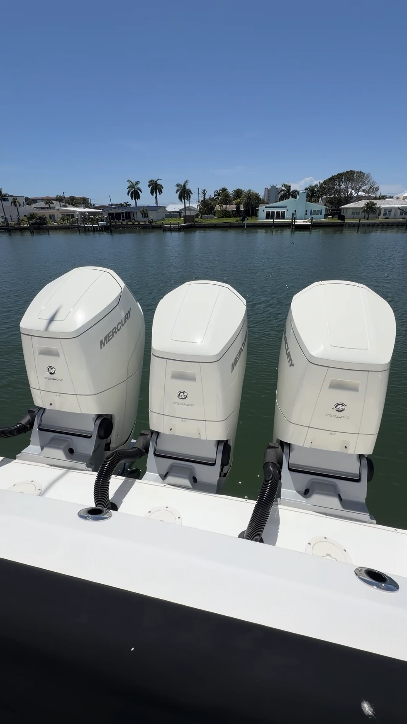 Three white Mercury outboard motor cowlings at a waterfront dock