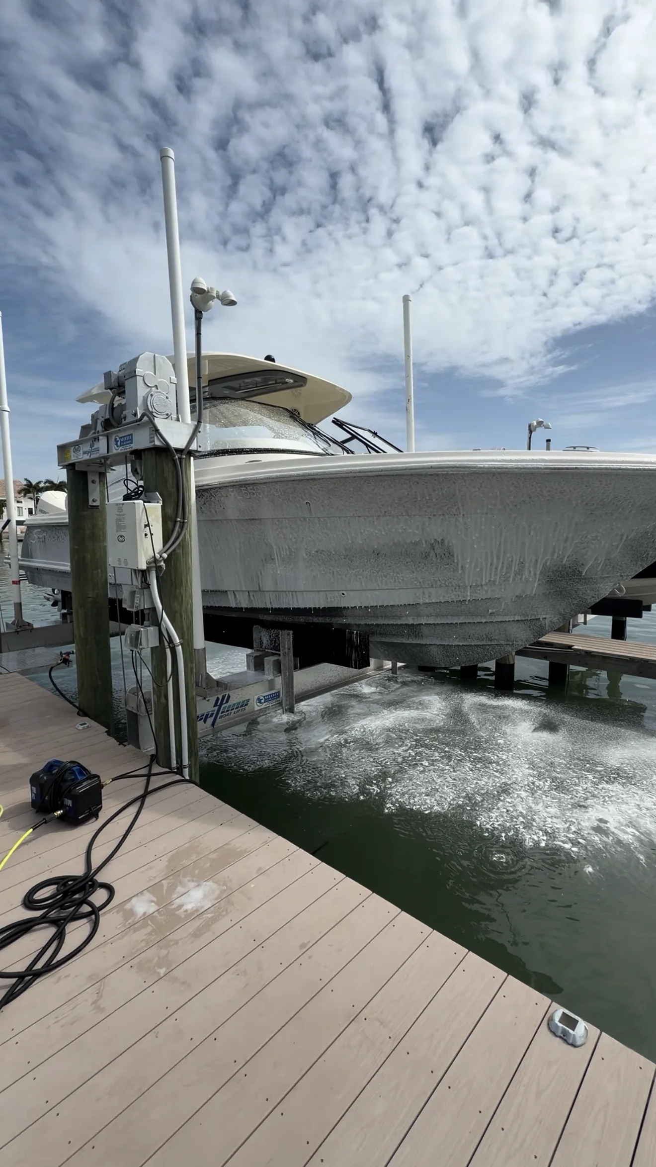 Boat covered in wash foam while raised on a waterfront lift
