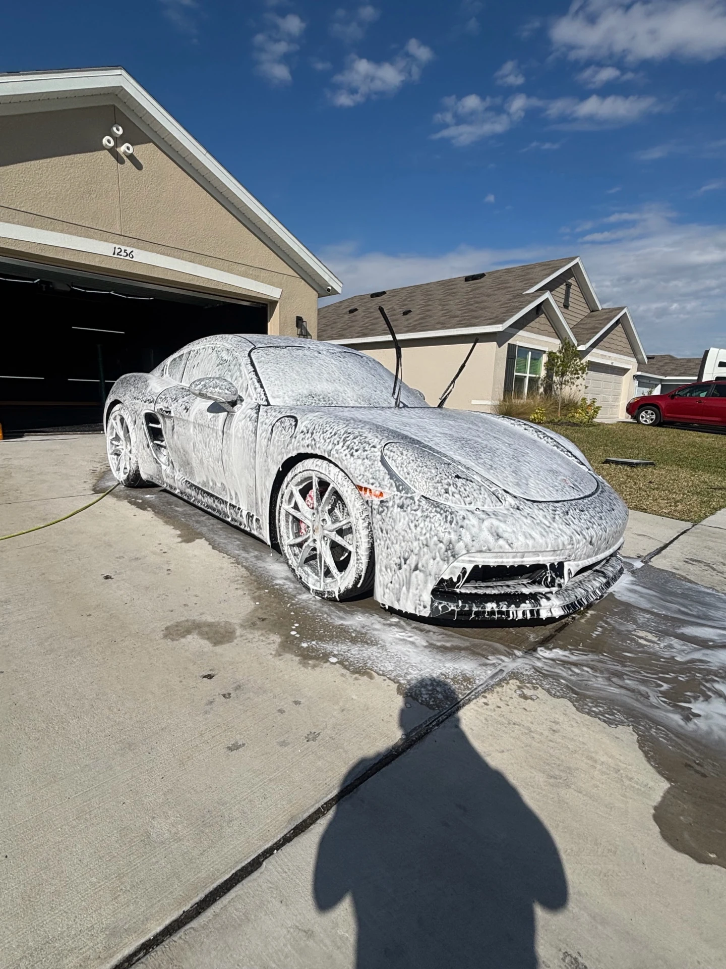 White sports car covered in wash foam during exterior preparation